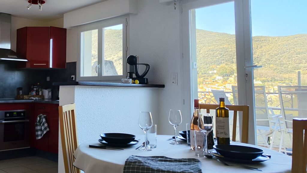 Living room dining table beside the equipped kitchen and terrace doors